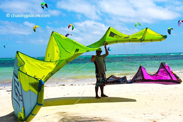 A local trainer preparing a kite while seeking some shade.